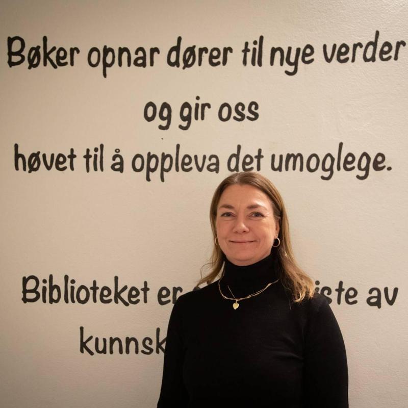 Karen Hognestad Liland, o BiblioteKaren, è davanti a una parete con la citazione: «I libri aprono le porte a nuovi mondi e ci danno la possibilità di vivere l’impossibile».