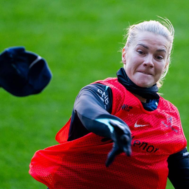 Foto: Fredrik Varfjell / NTB Una calciatrice con una pettorina rossa si toglie una felpa scura durante un allenamento su un campo erboso. (La descrizione dell’immagine è stata generata da un servizio di IA)