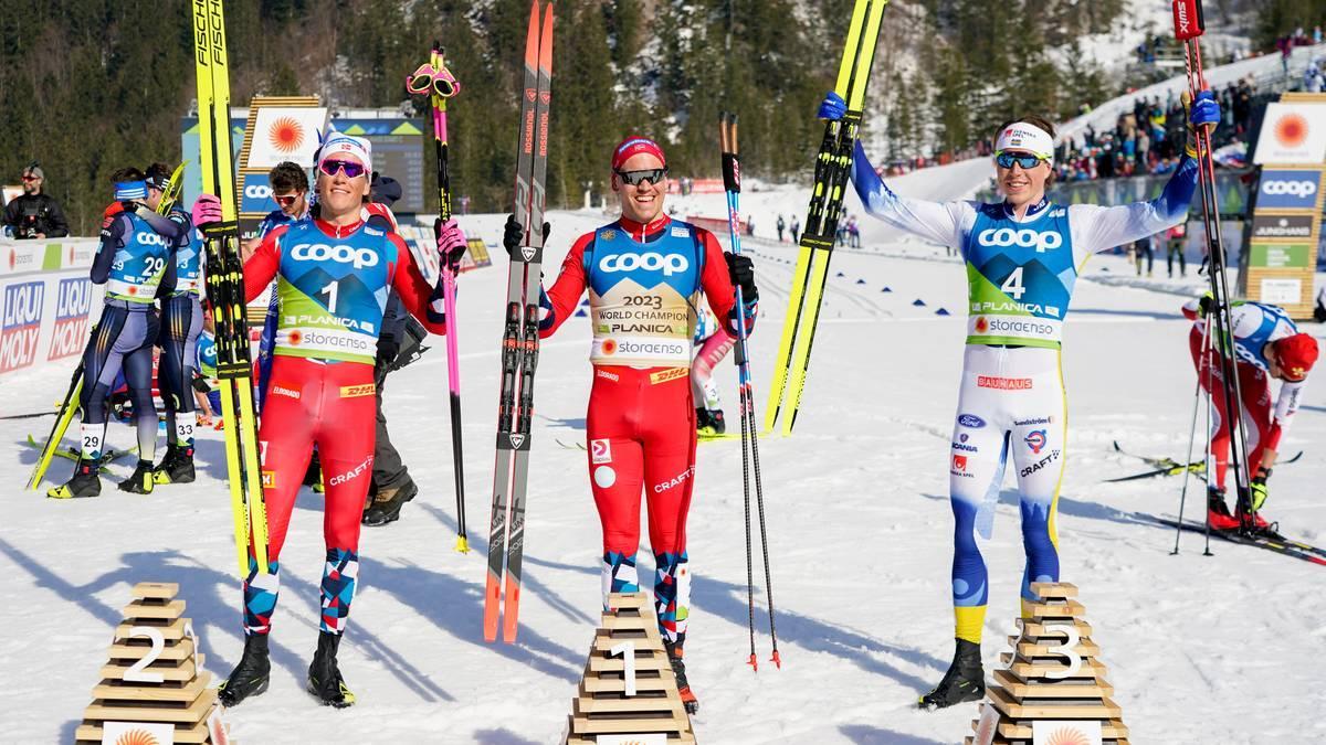 Foto: Terje Pedersen / NTB Tre fondisti sono sul podio dopo la cerimonia di premiazione a Planica. Tengono in mano sci e bastoncini. (La descrizione dell’immagine è stata generata da un servizio di IA)