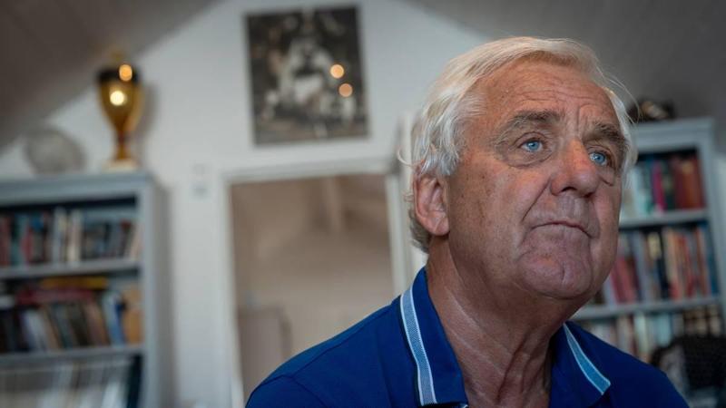 Foto: Odd Rune Kyllingstad / NRK Un uomo dai capelli grigi con una camicia blu, con scaffali di libri sullo sfondo. (La descrizione dell’immagine è stata generata da un servizio di IA)