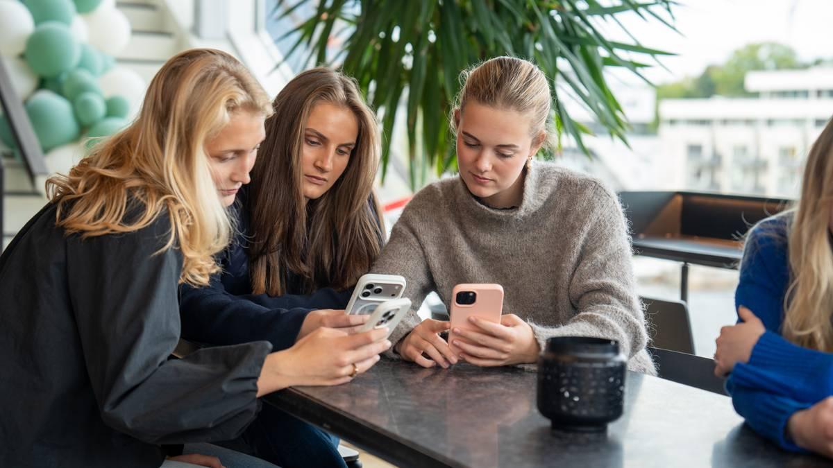 Foto: Elina Louise Karlsen Storheil / NRK Tre giovani donne sono sedute a un tavolo e guardano ciascuna il proprio cellulare. (Descrizione dell’immagine generata da un servizio di IA)