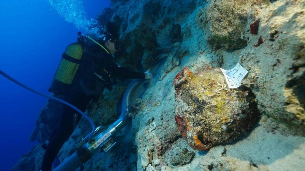 Un subacqueo recupera ceramiche da un sito archeologico sottomarino