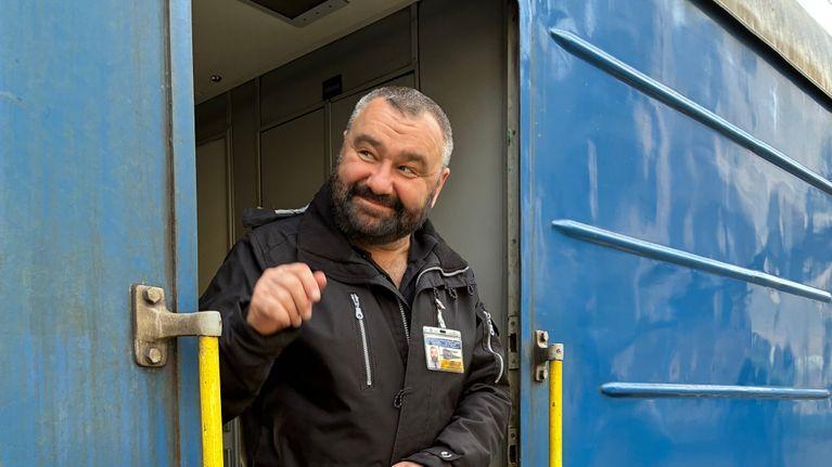 None Un capotreno è sulla porta del treno e controlla il binario.