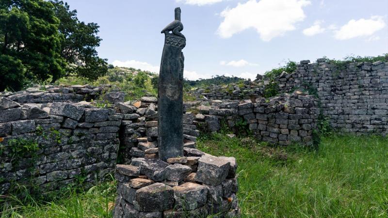 una scultura alta in pietra saponaria raffigurante un uccello si erge al centro di un cerchio di pietre