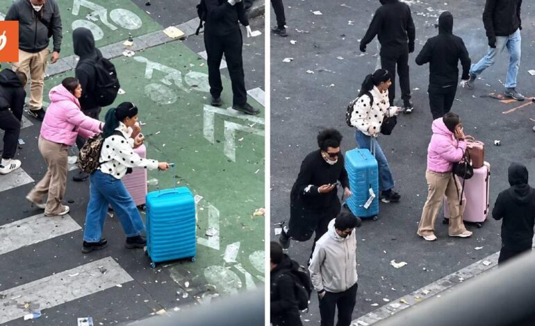 Turiste con le valigie attraversano le proteste senza fermarsi