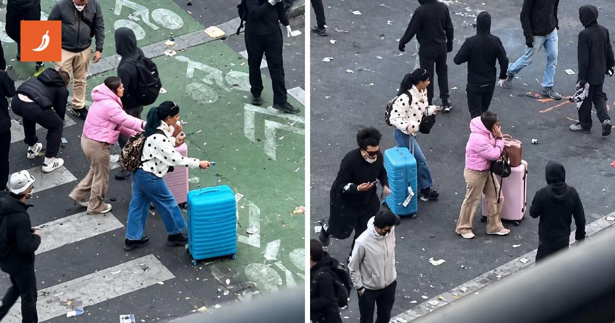Turiste con le valigie attraversano le proteste senza fermarsi