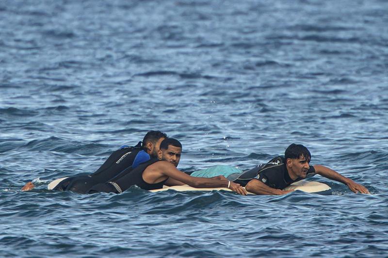 Uno dei migranti guarda la macchina fotografica mentre nuotano verso l’interno.