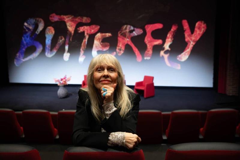 Foto: Siv Kristin Sællmann / nrk Una donna con lunghi capelli grigi sorride. È seduta in una sala cinematografica, con le spalle rivolte allo schermo.